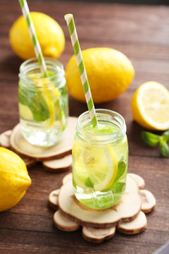 Fresh lemonade with lemon on brown wooden background