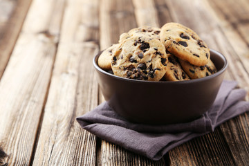 Chocolate chip cookies in bowl on brown wooden background