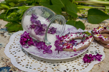 Naklejka premium Candied lilac flowers in a glass jar and cookies