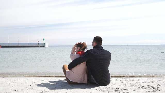 Couple sitting on beach enjoying sea view