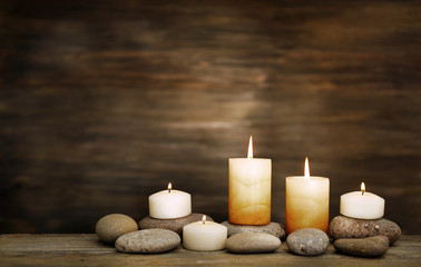 Fototapeta na wymiar Beautiful composition with candles and spa stones on wooden background