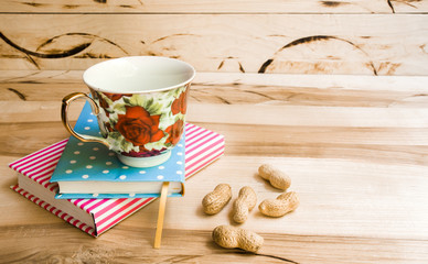 Cup of coffee on saucer with notebook on wooden table background