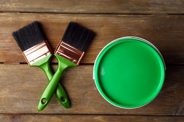 Paint can and paint brushes on wooden background
