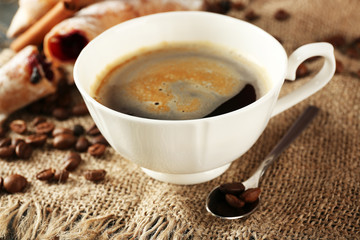Cup of coffee with beans on table, closeup