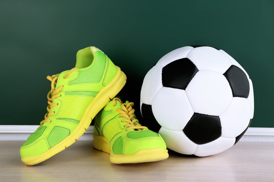 Sport shoes and soccer ball on blackboard background