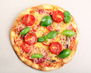 Tasty pizza with vegetables and basil in cardboard box close up