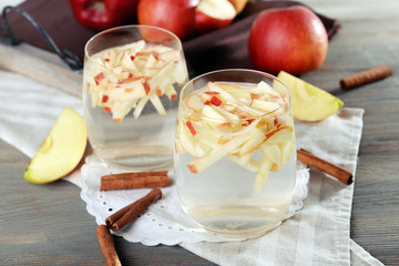 Glasses of apple cider with fruits and cinnamon on table close up