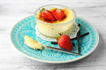 Creme brulee dessert with fresh strawberry berries on napkin, on color wooden background