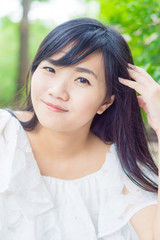 Fototapeta premium Portrait of young smiling Asian woman in park