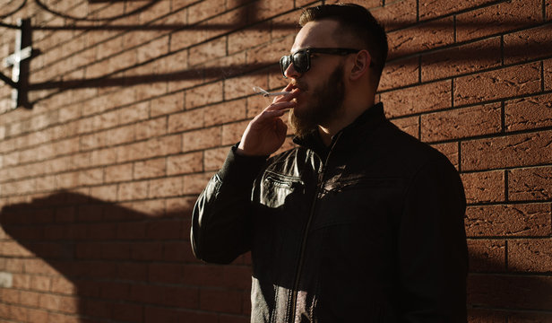 Side View Of Handsome Bearded Man Smoking A Cigarette