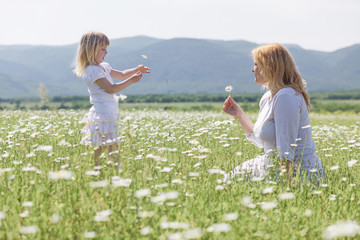 Happy mother playing with her daughter in flower field