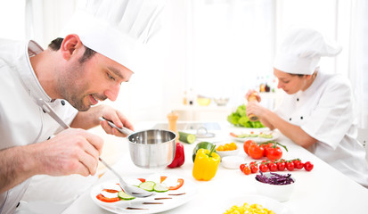 Young attractive professional chef cooking in his kitchen