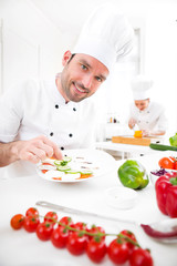 Young attractive professional chef cooking in his kitchen