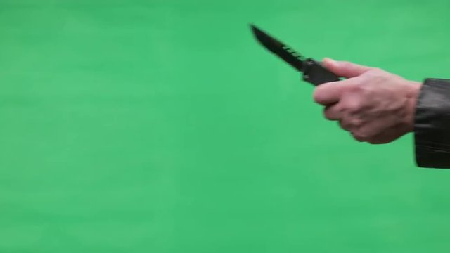 Hand Brandishing OTF Switch Blade Knife Over Green Screen