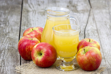 Apple juice and apples on wooden background