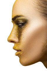 Portrait of a woman in profile with a golden creative make-up