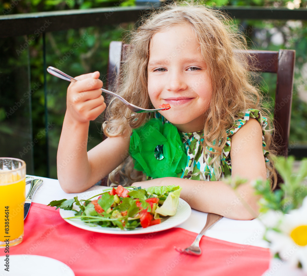 Wall mural child eating salad at a cafe