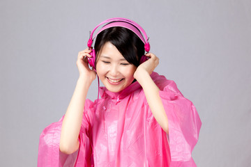ヘッドホンで音楽を聴くレインコートの女性
