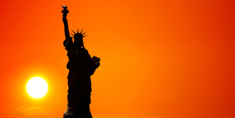 Statue of Liberty. Sun and orange sky in the background.