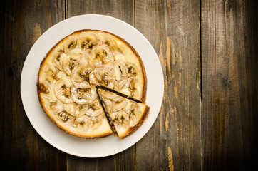 Banana caramel cheesecake on wooden background