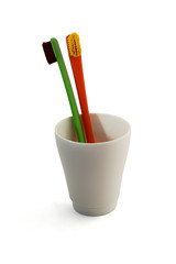 Зубные щетки в белом стакане на белом фоне