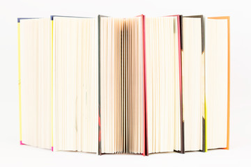 Stack of colorful books are standing on the edge.