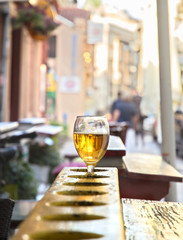 Glass of beer in wooden holder, in front of cafe 