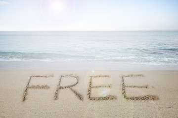 Free word handwritten in sand on sunny beach
