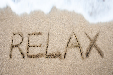 Fototapeta premium Relax word handwritten in sand on beach