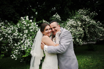 Wedding couple in love near white flowers trees