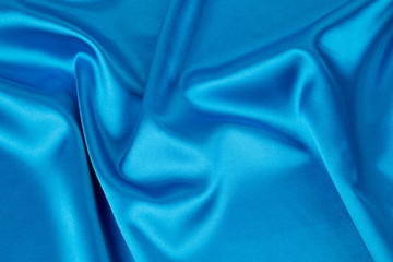 Soft folds of blue silk cloth texture.