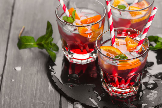 Red cool cocktail with oranges, soda, raspberry syrup, mint 