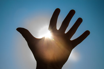 Sonne, Sonnenstrahl durch Hand mit Himmel im Hintergrund