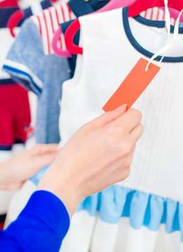 Woman's hand choosing child dress at clothing store.