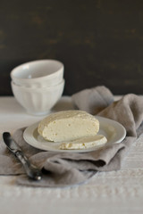 homemade cheese on a white plate on a light wooden surface
