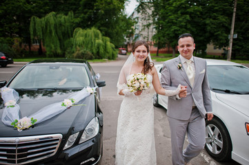 Wedding couple in love near wedding cars