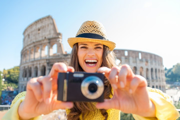 Obraz premium Laughing woman looks up from taking photo with Colosseum behind