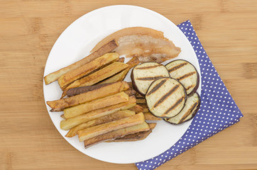 Fries potatoes with grilled eggplant on wooden background