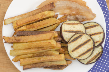 Fries potatoes with grilled eggplant on wooden background