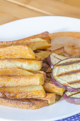 Fries potatoes with grilled eggplant on wooden background