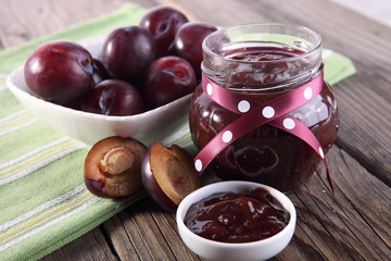 plums and jar of jam on table 