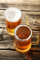 Two mug of beer on brown wooden background