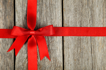 Red ribbon with bow on grey wooden background