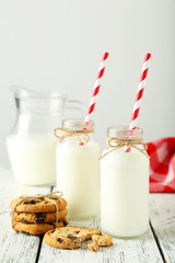 Two bottles of milk with striped straws on wooden background