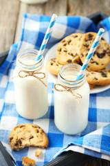 Two bottles of milk with striped straws and plate of cookies 