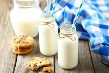 Two bottles of milk with striped straws and cookies 
