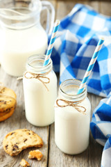 Two bottles of milk with striped straws and cookies 