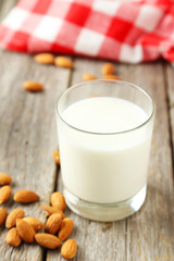 Glass of milk with almonds on grey wooden background