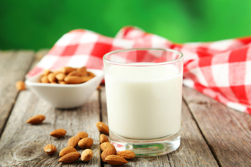 Glass of milk with almonds on grey wooden background