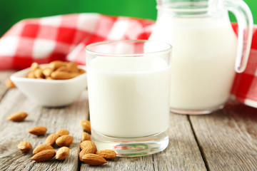 Glass of milk with almonds on grey wooden background